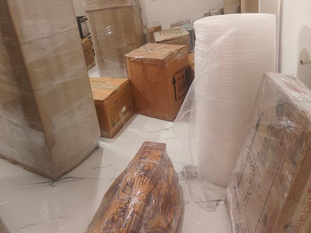 Bubble wrap roll, fragile-marked cartons and stretch-wrapped furniture inside a home